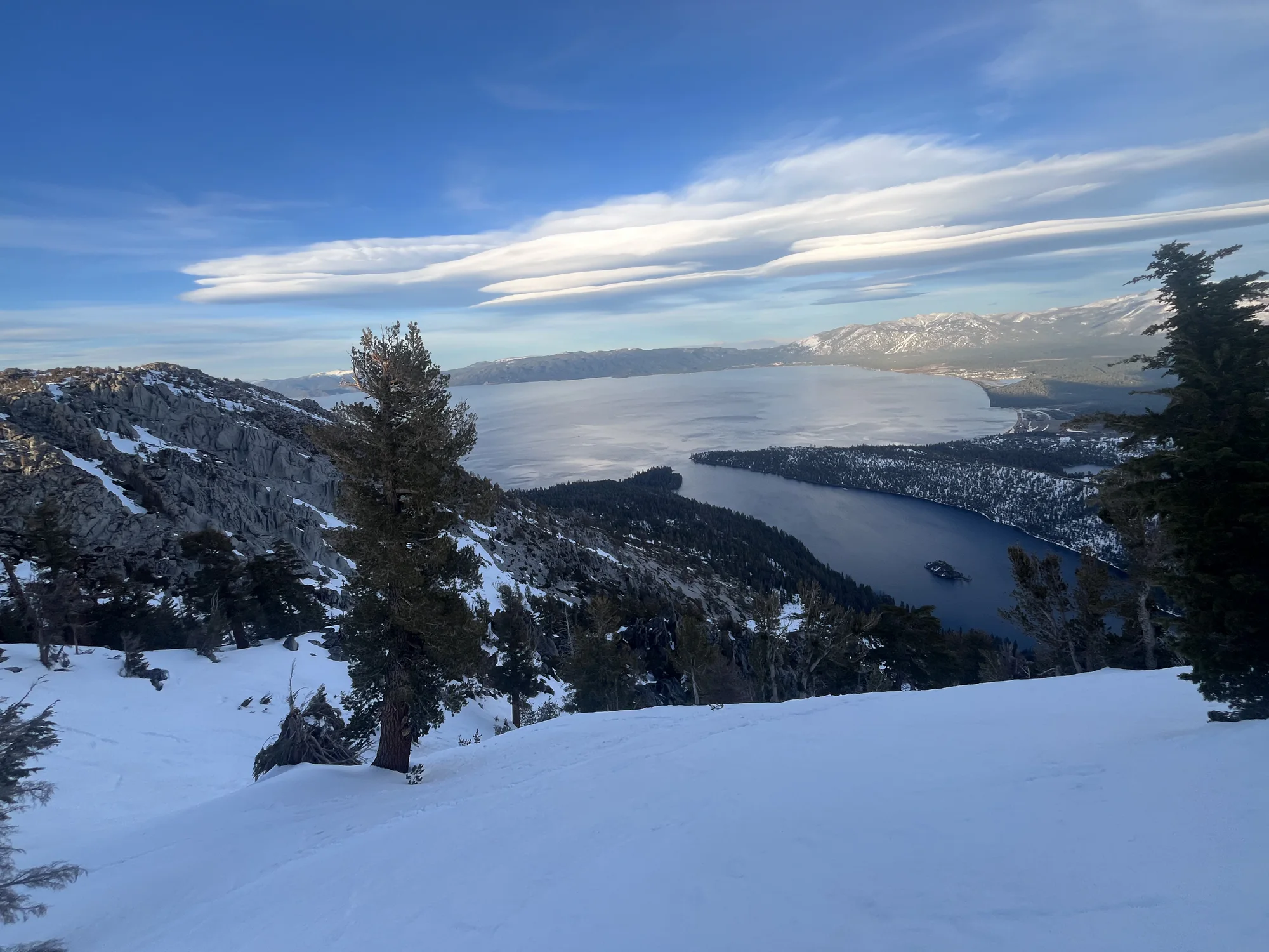 A snowy backcountry view across Lake Tahoe toward the surrounding mountains