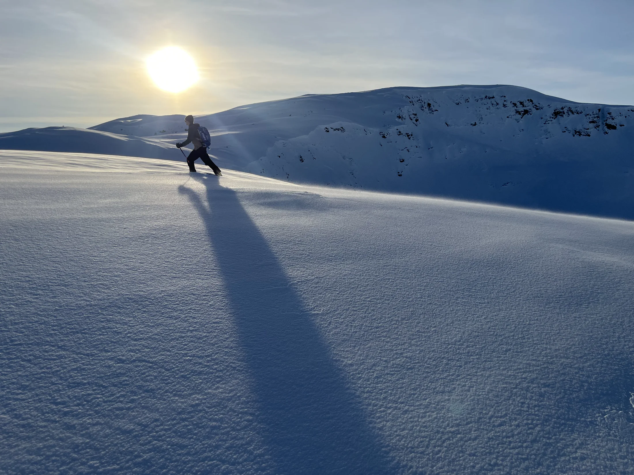 A backcountry traveler crossing a wind-textured snowy landscape
